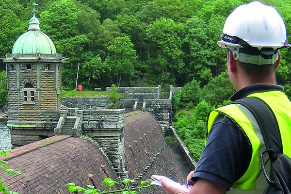 Picture of a man with a hard hat inspecting a dam in the UK