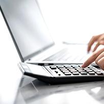 View of someone's hands using a calculator in front of laptop